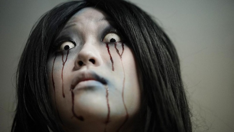 Casts as zombies perform by the window of a vehicle during a demonstration of a drive-in haunted house show at a garage Tuesday, Aug. 18, 2020, in Tokyo. Visitors remain in vehicles as taking prevention measures against the COVID-19 pandemic, while ghosts, zombies and other characters spook the visitors. Visitors could experience the entertainment with the safety of being inside their own vehicles. Or, a vehicle provided by the program is also available for rent at the site. (AP Photo/Eugene Hoshiko)