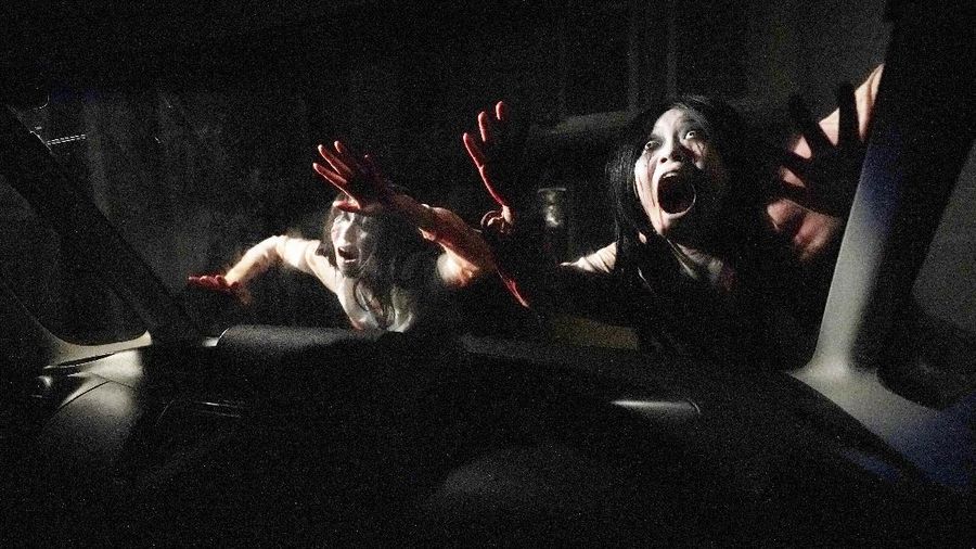 Casts as zombies perform by the window of a vehicle during a demonstration of a drive-in haunted house show at a garage Tuesday, Aug. 18, 2020, in Tokyo. Visitors remain in vehicles as taking prevention measures against the COVID-19 pandemic, while ghosts, zombies and other characters spook the visitors. Visitors could experience the entertainment with the safety of being inside their own vehicles. Or, a vehicle provided by the program is also available for rent at the site. (AP Photo/Eugene Hoshiko)