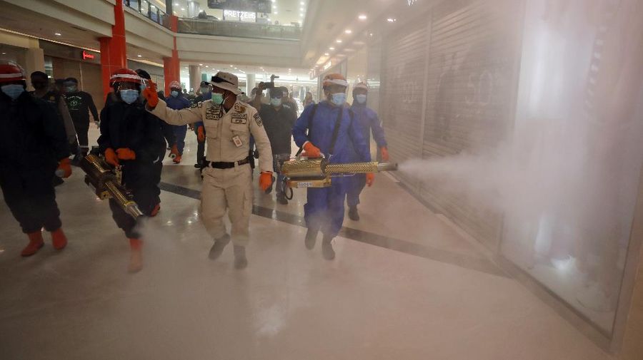 Indonesian firemen spray disinfectant to help curb the spread of the new coronavirus outbreak at Margo City shopping mall, which has been closed after a number of employees of a supermarket at the mall were tested positive for the virus, in Depok, Indonesia, Saturday, Aug. 22, 2020. (AP Photo/Dita Alangkara)