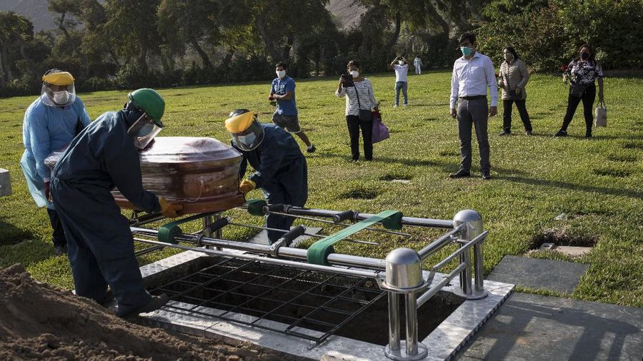 A Catholic priest prays during the burial of TV news cameraman Mario Bucana, who died of COVID-19, at a cemetery in Lima, Peru, Thursday, May 28, 2020. Dozens of journalists have died from COVID-19 in Peru since the pandemic began, in the highest reported death toll of media workers from the new coronavirus in any Latin American country, according to journalists’ groups that are monitoring available data. (AP Photo/Rodrigo Abd)