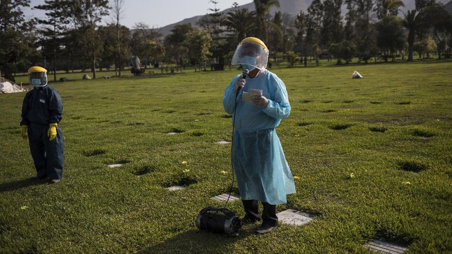 A Catholic priest prays during the burial of TV news cameraman Mario Bucana, who died of COVID-19, at a cemetery in Lima, Peru, Thursday, May 28, 2020. Dozens of journalists have died from COVID-19 in Peru since the pandemic began, in the highest reported death toll of media workers from the new coronavirus in any Latin American country, according to journalists’ groups that are monitoring available data. (AP Photo/Rodrigo Abd)
