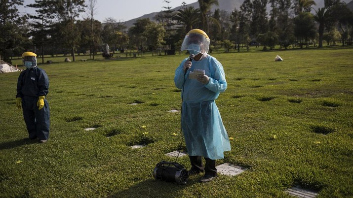 A Catholic priest prays during the burial of TV news cameraman Mario Bucana, who died of COVID-19, at a cemetery in Lima, Peru, Thursday, May 28, 2020. Dozens of journalists have died from COVID-19 in Peru since the pandemic began, in the highest reported death toll of media workers from the new coronavirus in any Latin American country, according to journalists’ groups that are monitoring available data. (AP Photo/Rodrigo Abd)