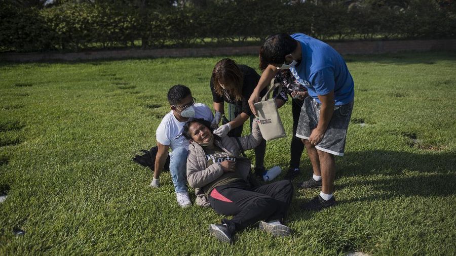 A Catholic priest prays during the burial of TV news cameraman Mario Bucana, who died of COVID-19, at a cemetery in Lima, Peru, Thursday, May 28, 2020. Dozens of journalists have died from COVID-19 in Peru since the pandemic began, in the highest reported death toll of media workers from the new coronavirus in any Latin American country, according to journalists’ groups that are monitoring available data. (AP Photo/Rodrigo Abd)