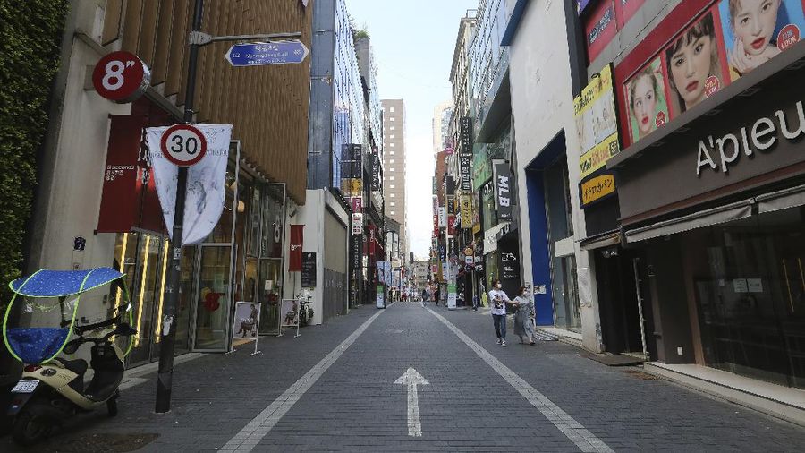 A couple wearing face masks to help protect against the spread of the coronavirus walks along on a nearly empty shopping street in Seoul, South Korea, Sunday, Aug. 23, 2020. (AP Photo/Ahn Young-joon)