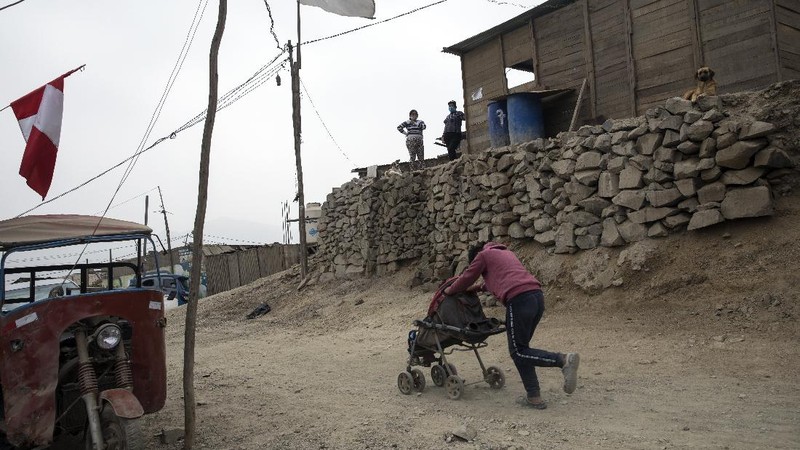 Jenny Diaz begs in the middle of a road while carrying her daughter Aina Flores, 1, on the outskirts of Lima, Peru, Saturday, Aug.22, 2020, amid the coronavirus pandemic. (AP Photo/Rodrigo Abd)