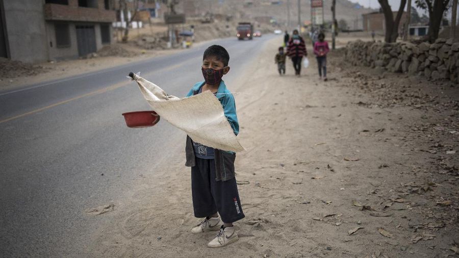 Jenny Diaz begs in the middle of a road while carrying her daughter Aina Flores, 1, on the outskirts of Lima, Peru, Saturday, Aug.22, 2020, amid the coronavirus pandemic. (AP Photo/Rodrigo Abd)