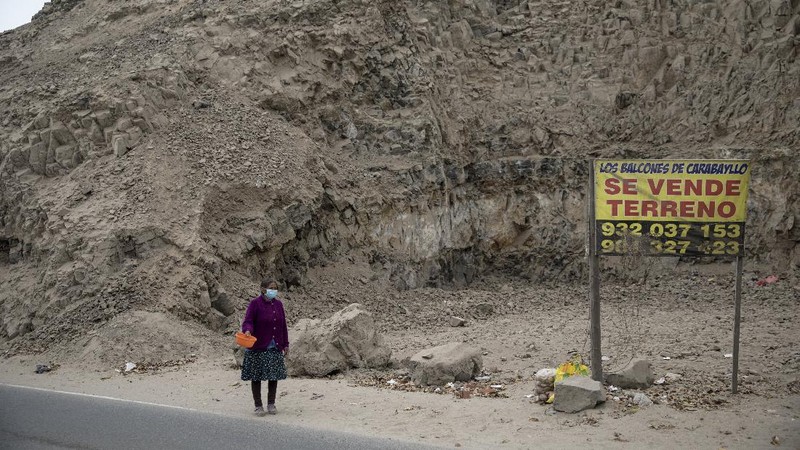 Jenny Diaz begs in the middle of a road while carrying her daughter Aina Flores, 1, on the outskirts of Lima, Peru, Saturday, Aug.22, 2020, amid the coronavirus pandemic. (AP Photo/Rodrigo Abd)