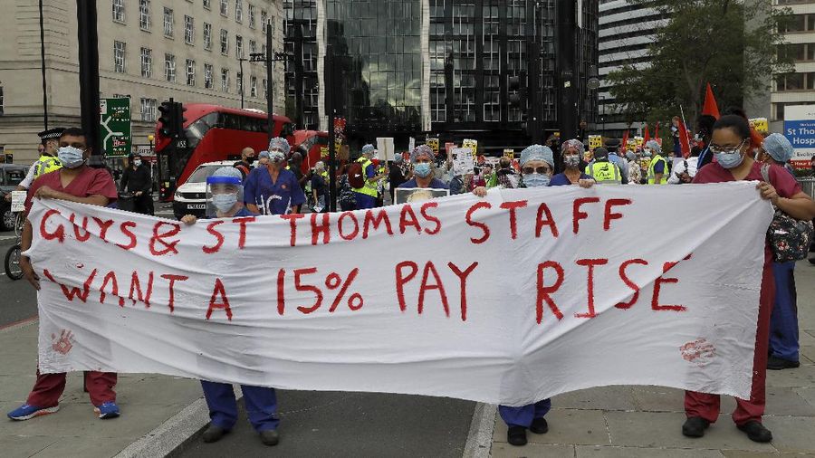 Anggota perawat dan staf Layanan Kesehatan Nasional Inggris (NHS) melakukan aksi di tengah penyebaran penyakit COVID-19, di luar Downing Street di London, Inggris. (AP/Kirsty Wigglesworth)