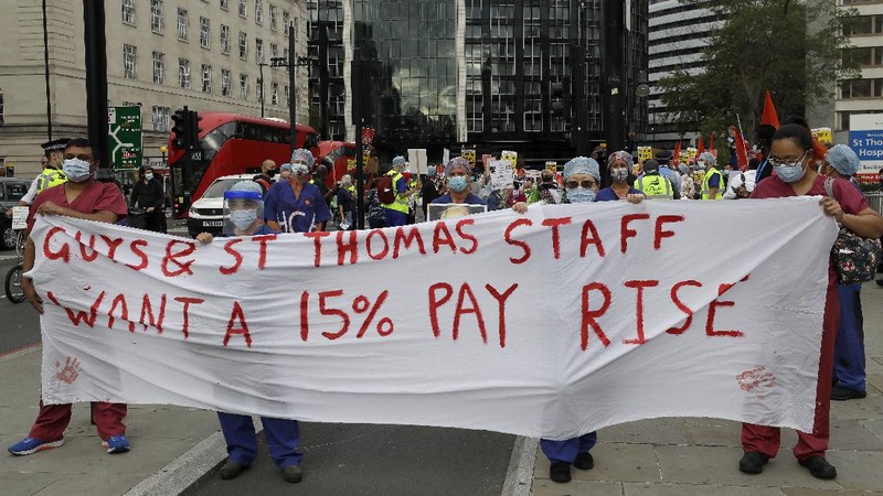 Anggota perawat dan staf Layanan Kesehatan Nasional Inggris (NHS) melakukan aksi di tengah penyebaran penyakit COVID-19, di luar Downing Street di London, Inggris. (AP/Kirsty Wigglesworth)