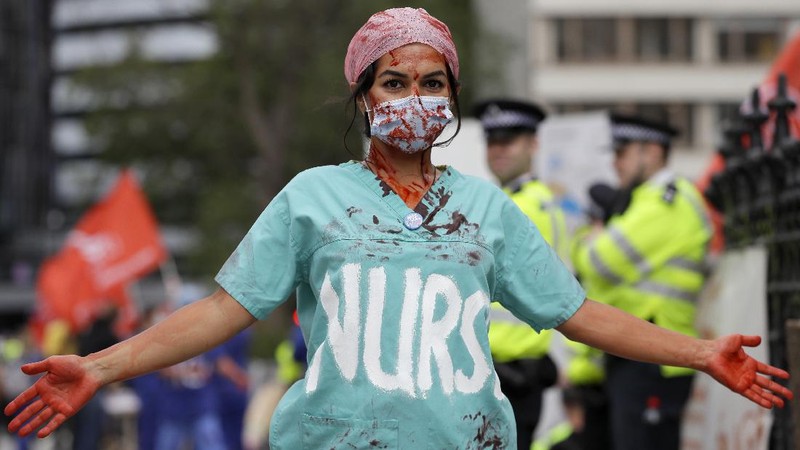 Anggota perawat dan staf Layanan Kesehatan Nasional Inggris (NHS) melakukan aksi di tengah penyebaran penyakit COVID-19, di luar Downing Street di London, Inggris. (AP/Kirsty Wigglesworth)