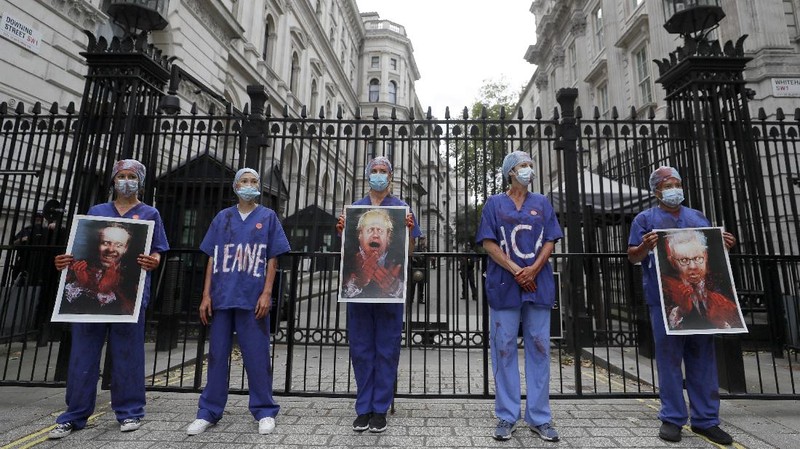Anggota perawat dan staf Layanan Kesehatan Nasional Inggris (NHS) melakukan aksi di tengah penyebaran penyakit COVID-19, di luar Downing Street di London, Inggris. (AP/Kirsty Wigglesworth)