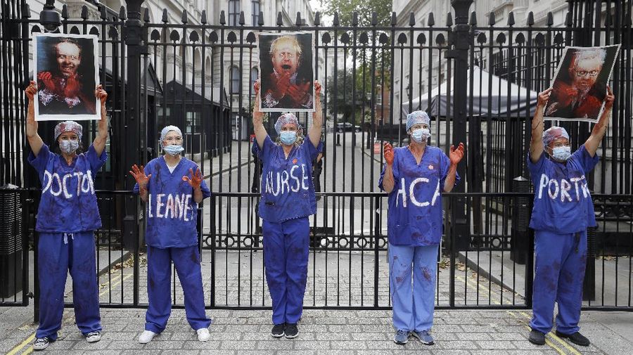 Anggota perawat dan staf Layanan Kesehatan Nasional Inggris (NHS) melakukan aksi di tengah penyebaran penyakit COVID-19, di luar Downing Street di London, Inggris. (AP/Kirsty Wigglesworth)