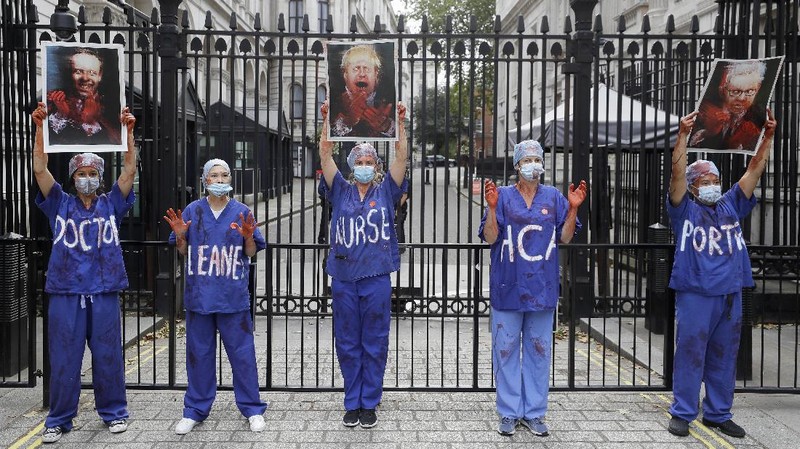 Anggota perawat dan staf Layanan Kesehatan Nasional Inggris (NHS) melakukan aksi di tengah penyebaran penyakit COVID-19, di luar Downing Street di London, Inggris. (AP/Kirsty Wigglesworth)