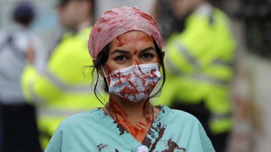 Anggota perawat dan staf Layanan Kesehatan Nasional Inggris (NHS) melakukan aksi di tengah penyebaran penyakit COVID-19, di luar Downing Street di London, Inggris. (AP/Kirsty Wigglesworth)