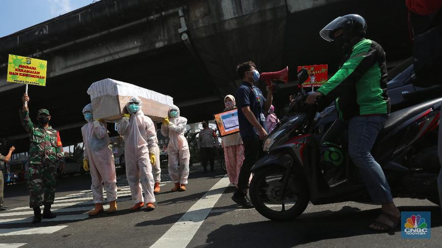 Petugas gabungan dari Kecamatan Cilandak dan Polsek Cilandak mengarak instalasi peti mati jenazah Covid-19 saat melakukan sosialisasi bahaya virus Covid-19 di kawasan Fatmawati, Jakarta. (CNBC Indonesia/Andrean Kristianto)