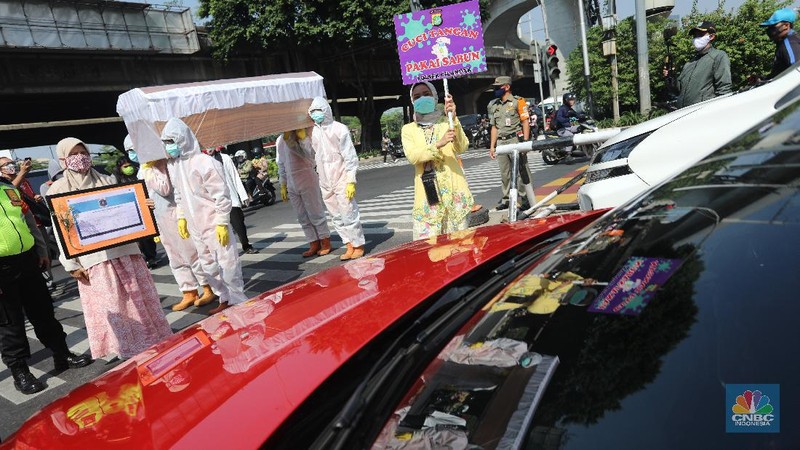 Petugas gabungan dari Kecamatan Cilandak dan Polsek Cilandak mengarak instalasi peti mati jenazah Covid-19 saat melakukan sosialisasi bahaya virus Covid-19 di kawasan Fatmawati, Jakarta. (CNBC Indonesia/Andrean Kristianto)