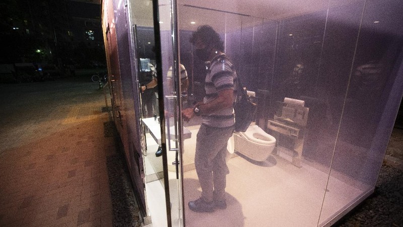 A man gets out of one of the transparent glass toilets after use at Yoyogi Hukamachi Mini Park in Tokyo on Thursday, Aug. 20, 2020. The bathrooms with the tinted wall turn opaque when it's in use. The walls of two newly installed public toilets in Tokyo's Shibuya neighborhood are see-through before people enter, but turn opaque when the doors are closed and locked from the inside. The so-called transparent toilets, which opened this month, were designed by award-winning Japanese architect Shigeru Ban for a project organized by The Nippon Foundation that redesigned a total of 17 public toilets in the neighborhood. (AP Photo/Hiro Komae)
