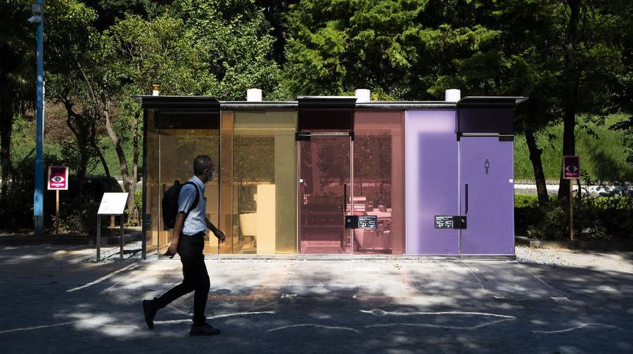 A man gets out of one of the transparent glass toilets after use at Yoyogi Hukamachi Mini Park in Tokyo on Thursday, Aug. 20, 2020. The bathrooms with the tinted wall turn opaque when it's in use. The walls of two newly installed public toilets in Tokyo's Shibuya neighborhood are see-through before people enter, but turn opaque when the doors are closed and locked from the inside. The so-called transparent toilets, which opened this month, were designed by award-winning Japanese architect Shigeru Ban for a project organized by The Nippon Foundation that redesigned a total of 17 public toilets in the neighborhood. (AP Photo/Hiro Komae)