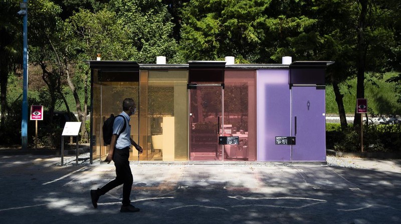 A man gets out of one of the transparent glass toilets after use at Yoyogi Hukamachi Mini Park in Tokyo on Thursday, Aug. 20, 2020. The bathrooms with the tinted wall turn opaque when it's in use. The walls of two newly installed public toilets in Tokyo's Shibuya neighborhood are see-through before people enter, but turn opaque when the doors are closed and locked from the inside. The so-called transparent toilets, which opened this month, were designed by award-winning Japanese architect Shigeru Ban for a project organized by The Nippon Foundation that redesigned a total of 17 public toilets in the neighborhood. (AP Photo/Hiro Komae)