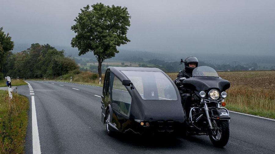 Joerg Grossmann drives his motorcycle combination with a Harley E Glide fitted with a sidecar on a road near Anspach, Germany, on Monday, Aug. 31, 2020. The 56 year old Grossmann who calls himself a chauffeur for the deceased, developed his motorbike hearse for die-hard bikers who want a last ride to their final resting place. in Frankfurt, (AP Photo/Michael Probst)