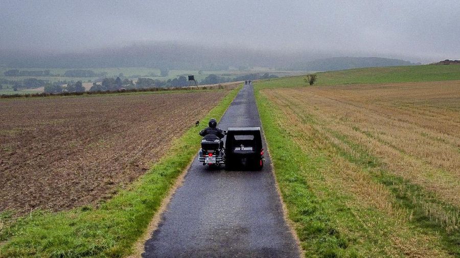 Joerg Grossmann drives his motorcycle combination with a Harley E Glide fitted with a sidecar on a road near Anspach, Germany, on Monday, Aug. 31, 2020. The 56 year old Grossmann who calls himself a chauffeur for the deceased, developed his motorbike hearse for die-hard bikers who want a last ride to their final resting place. in Frankfurt, (AP Photo/Michael Probst)