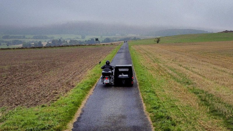 Joerg Grossmann drives his motorcycle combination with a Harley E Glide fitted with a sidecar on a road near Anspach, Germany, on Monday, Aug. 31, 2020. The 56 year old Grossmann who calls himself a chauffeur for the deceased, developed his motorbike hearse for die-hard bikers who want a last ride to their final resting place. in Frankfurt, (AP Photo/Michael Probst)