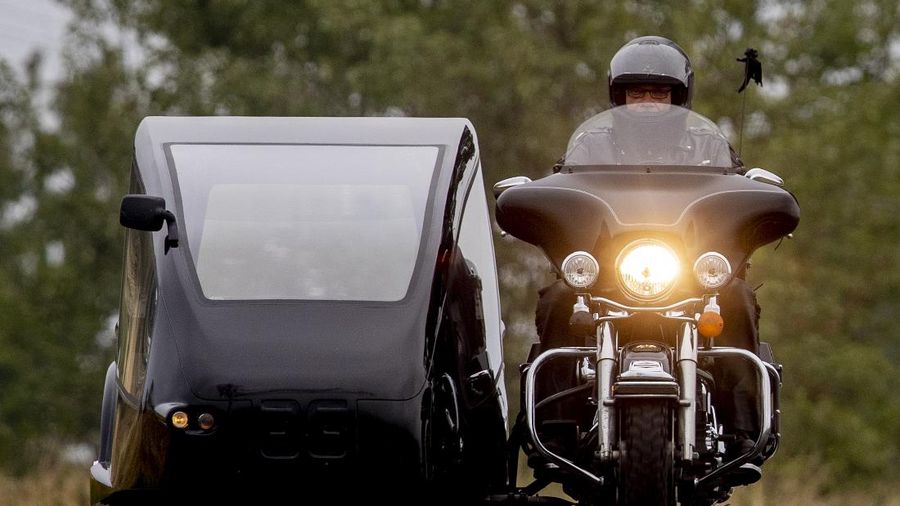 Joerg Grossmann drives his motorcycle combination with a Harley E Glide fitted with a sidecar on a road near Anspach, Germany, on Monday, Aug. 31, 2020. The 56 year old Grossmann who calls himself a chauffeur for the deceased, developed his motorbike hearse for die-hard bikers who want a last ride to their final resting place. in Frankfurt, (AP Photo/Michael Probst)
