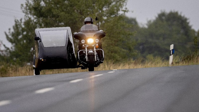 Joerg Grossmann drives his motorcycle combination with a Harley E Glide fitted with a sidecar on a road near Anspach, Germany, on Monday, Aug. 31, 2020. The 56 year old Grossmann who calls himself a chauffeur for the deceased, developed his motorbike hearse for die-hard bikers who want a last ride to their final resting place. in Frankfurt, (AP Photo/Michael Probst)