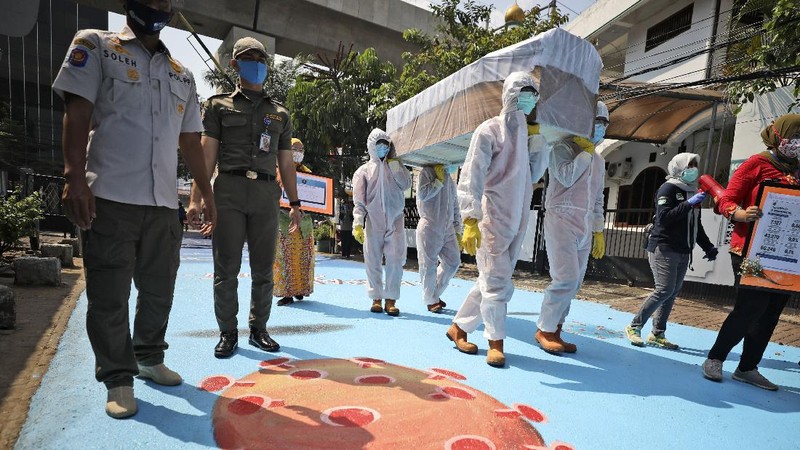 A worker climbs a ladder as he installs a coronavirus awareness-themed banner bearing a portrait of President Joko Widodo wearing a face mask, in Jakarta, Indonesia, Wednesday, Aug. 26, 2020. Writings on the banner read 
