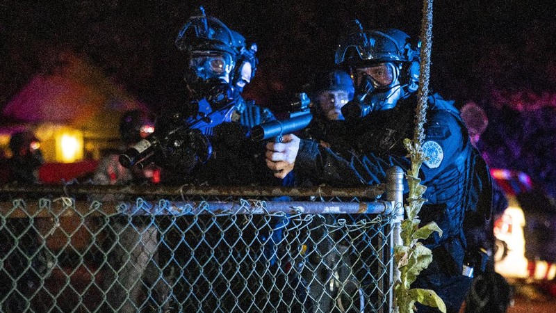 Police officers pass a fire lit by protesters on Saturday, Sept. 5, 2020, in Portland, Ore. Hundreds of people gathered for rallies and marches against police violence and racial injustice Saturday night in Portland, Oregon, as often violent nightly demonstrations that have happened for 100 days since George Floyd was killed showed no signs of ceasing. (AP Photo/Noah Berger)