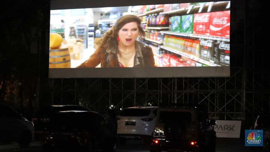 Sejumlah mobil terparkir di bioskop Skylight Cinema Senayan Park, Jakarta, Rabu (9/9/2020). Pandemi Covid-19 menimbulkan gaya hidup baru dalam menonton film. (CNBC Indonesia/Tri Susilo)

Gaya hidup baru menonton film itu dapat disaksikan di mall terbaru di Jakarta Pusat bernama Senayan Park, Sebuah bioskop dengan konsep drive in ditampilkan.  

Bioskop bernama Skylight Cinema itu hadir mulai 5 September sampai 30 September 2020.

Di bioskop tersebut penonton tidak mendapatkan bangku untuk menonton film. Melainkan mereka akan menonton di dalam mobil masing-masing yang diparkir di sebuah halaman luas.

Skylight Cinema menyediakan dua cinema yang dapat menampung 105 mobil setiap sesinya.

Ada dua sesi pemutaran film setiap harinya yakni sesi pukul 18.30 WIB dan sesi 21.30 WIB.   

Sehingga total ada 210 mobil dapat ditampung setiap hari dalam pemutaran film di Skylight Cinema.

Mobil-mobil terlihat mengantre masuk ke sebuah halaman cinema. Sebelum masuk para penonton dicek suhu tubuh terlebih dahulu.

Para penonton juga wajib menggunakan masker dan membawa handsanitizer sebelum mobil mereka masuk cinema. (CNBC Indonesia/Tri Susilo)