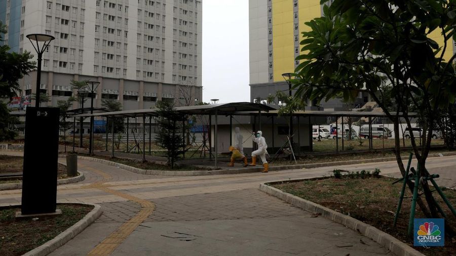 Tenaga kesehatan berjalan di kawasan zona merah Rumah Sakit Darurat Covid-19 Wisma Atlet, Kemayoran Jakarta, 11/9. Satuan Tugas (Satgas) Penanganan Covid-19 menyiapkan tower 5 yang direncanakan beroperasi malam ini untuk fasilitas isolasi mandiri bagi  pasien tanpa gejala. 
Kapasitas tower 5, memiliki  32 lantai 886 kamar di kali 2 bed jadi 1772 kamar tower 5. Koordinator Dokter Lapangan Observasi rumah sakit Darurat Wisma Atlet Muhammad Arifin mengatakan Tower 1-7 semua hidup karena pengecekan lampu. Tower 6&7 tidak full namun sudah terisi 70%.  (CNBC Indonesia/ Muhammad Sabki)