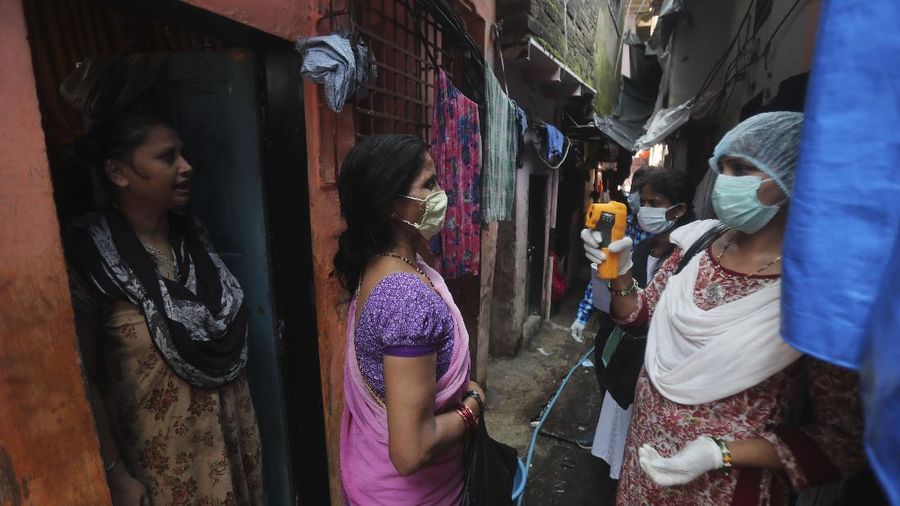 A woman wearing white protective gear, foreground, mourns after taking a glimpse of her husband's body, a victim of COVID 19, at a cremation site in Gauhati, India, Thursday, Sept. 10, 2020. Experts caution that India's outbreak is entering a more dangerous phase as the virus spreads to smaller towns and villages. (AP Photo/Anupam Nath)