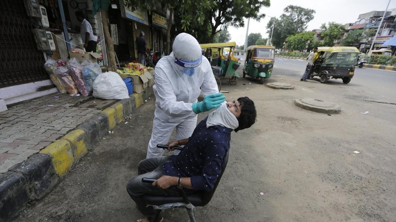 A woman wearing white protective gear, foreground, mourns after taking a glimpse of her husband's body, a victim of COVID 19, at a cremation site in Gauhati, India, Thursday, Sept. 10, 2020. Experts caution that India's outbreak is entering a more dangerous phase as the virus spreads to smaller towns and villages. (AP Photo/Anupam Nath)