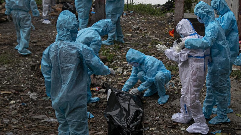A woman wearing white protective gear, foreground, mourns after taking a glimpse of her husband's body, a victim of COVID 19, at a cremation site in Gauhati, India, Thursday, Sept. 10, 2020. Experts caution that India's outbreak is entering a more dangerous phase as the virus spreads to smaller towns and villages. (AP Photo/Anupam Nath)
