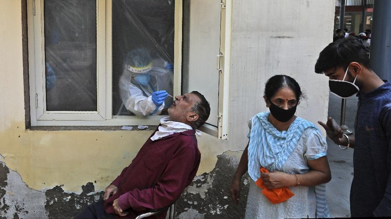 A woman wearing white protective gear, foreground, mourns after taking a glimpse of her husband's body, a victim of COVID 19, at a cremation site in Gauhati, India, Thursday, Sept. 10, 2020. Experts caution that India's outbreak is entering a more dangerous phase as the virus spreads to smaller towns and villages. (AP Photo/Anupam Nath)
