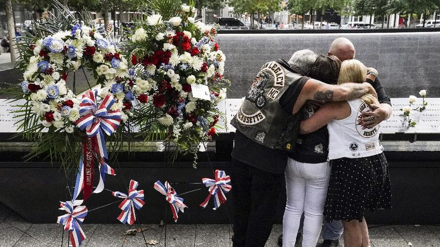 Mourners hug beside the names of the deceased Jesus Sanchez and Marianne MacFarlane at the National September 11 Memorial and Museum, Friday, Sept. 11, 2020, in New York. Americans commemorated 9/11 with tributes that have been altered by coronavirus precautions and woven into the presidential campaign. (AP Photo/John Minchillo)