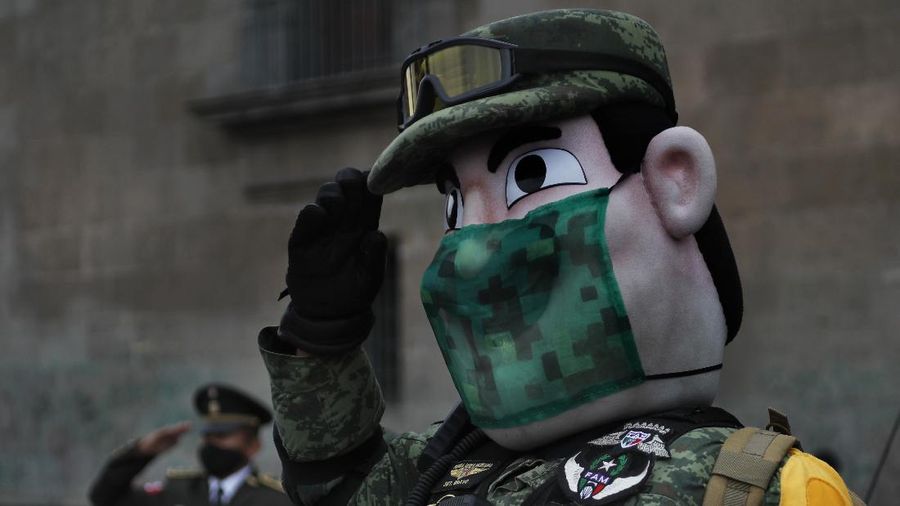 Medical workers who tend to COVID-19 patients and who received a medal from the government as recognition for their efforts pose for a photo with an Army mascot during the annual Independence Day military parade in Mexico City’s main square of the capital, the Zócalo, Wednesday, Sept. 16, 2020. Mexico celebrates the anniversary of its independence uprising of 1810. ( AP Photo/Marco Ugarte)
