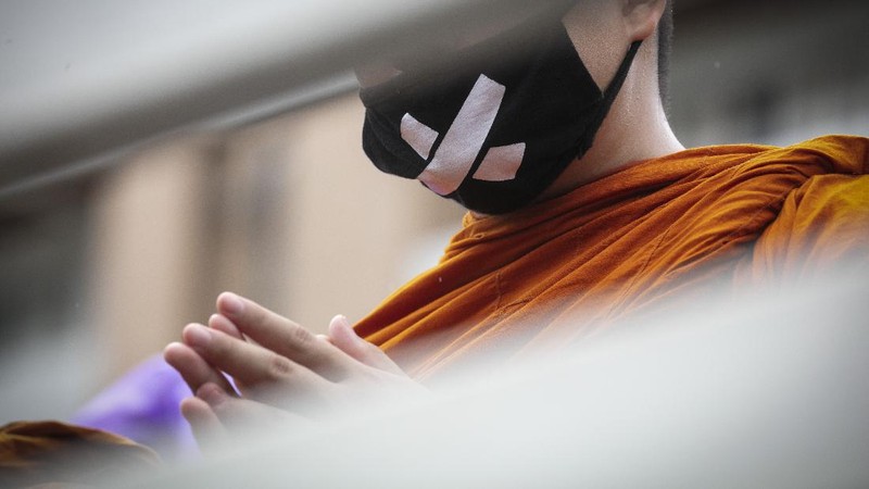 Pro-democracy protesters sit in front of a poster of the three finger symbol of resistance  during a protest outside Thammasat University in Bangkok, Thailand, Saturday, Sept. 19, 2020. Protesters gathered Saturday in Bangkok for what was expected to be the biggest rally yet in an ongoing campaign calling for a new election and democratic reforms. (AP Photo/Sakchai Lalit)