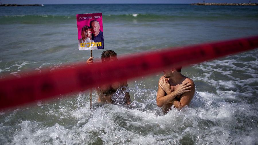 Acrobats perform as they wear face masks during a protest against government's decision to close beaches during the three-week nationwide lockdown due to the coronavirus pandemic, in Tel Aviv, Israel, Saturday, Sept 19, 2020. Israel went back into a full lockdown on Friday to try to contain a coronavirus outbreak that has steadily worsened for months as its government has been plagued by indecision and infighting. (AP Photo/Oded Balilty)