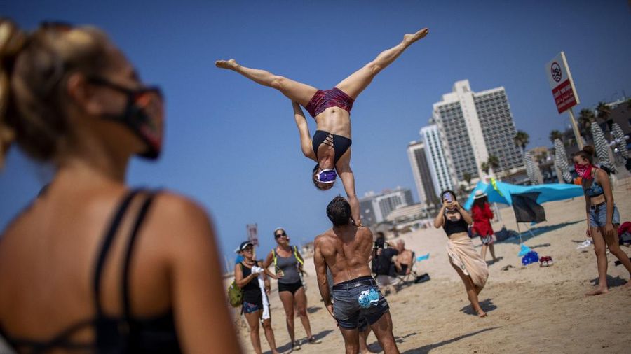 Acrobats perform as they wear face masks during a protest against government's decision to close beaches during the three-week nationwide lockdown due to the coronavirus pandemic, in Tel Aviv, Israel, Saturday, Sept 19, 2020. Israel went back into a full lockdown on Friday to try to contain a coronavirus outbreak that has steadily worsened for months as its government has been plagued by indecision and infighting. (AP Photo/Oded Balilty)
