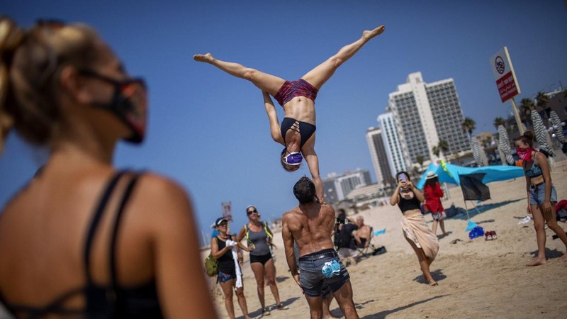 Acrobats perform as they wear face masks during a protest against government's decision to close beaches during the three-week nationwide lockdown due to the coronavirus pandemic, in Tel Aviv, Israel, Saturday, Sept 19, 2020. Israel went back into a full lockdown on Friday to try to contain a coronavirus outbreak that has steadily worsened for months as its government has been plagued by indecision and infighting. (AP Photo/Oded Balilty)