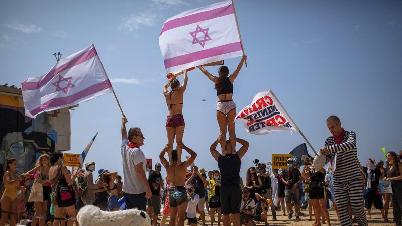 Acrobats perform as they wear face masks during a protest against government's decision to close beaches during the three-week nationwide lockdown due to the coronavirus pandemic, in Tel Aviv, Israel, Saturday, Sept 19, 2020. Israel went back into a full lockdown on Friday to try to contain a coronavirus outbreak that has steadily worsened for months as its government has been plagued by indecision and infighting. (AP Photo/Oded Balilty)