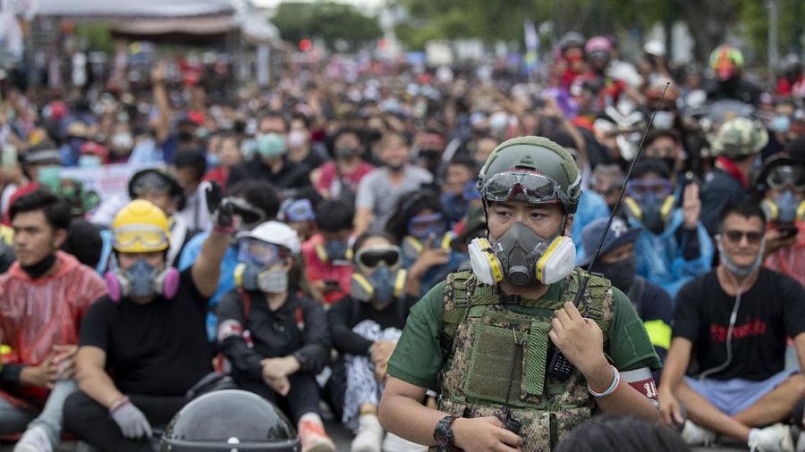 Pro-democracy protesters, some in protective tear-gas masks form a human chain during a street march close to Sanam Luang in Bangkok, Thailand, Sunday, Sept. 20, 2020. The mass student-led rally that began Saturday is the largest in a series of protests this year, with thousands camping overnight near the royal palace, demanding for new elections and reform of the monarchy.(AP Photo/Gemunu Amarasinghe)