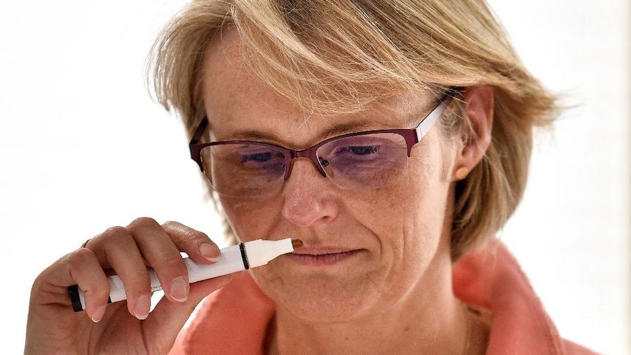 German Minister of Education and Research Anja Karliczek testing her sense of smell during an information visit about coronavirus research at the German Center for Neurodegenerative Diseases (DZNE) in Bonn, Germany, Monday, May 18, 2020. (AP Photo/Martin Meissner, Pool)
