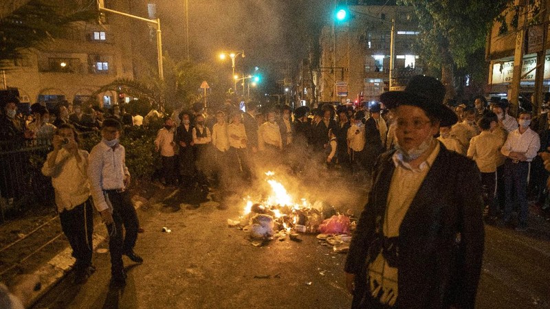 Garbage burns as ultra-Orthodox Jews protest against the restrictions on gatherings for public prayers despite a new nationwide lockdown order aimed at curbing a raging coronavirus outbreak in Bnei Brak, Israel, Sunday, Sept. 20, 2020. In the ultra-Orthodox town of Bnei Brak near Israel's commercial hub of Tel Aviv, over 100 activists took to the streets and burned garbage to protest restrictions on gatherings for public prayers. (AP Photo/Ariel Schalit)