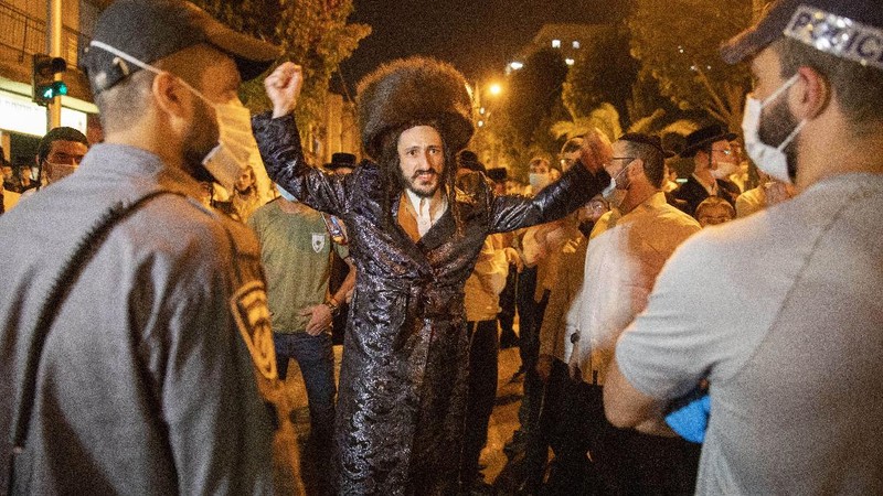 Garbage burns as ultra-Orthodox Jews protest against the restrictions on gatherings for public prayers despite a new nationwide lockdown order aimed at curbing a raging coronavirus outbreak in Bnei Brak, Israel, Sunday, Sept. 20, 2020. In the ultra-Orthodox town of Bnei Brak near Israel's commercial hub of Tel Aviv, over 100 activists took to the streets and burned garbage to protest restrictions on gatherings for public prayers. (AP Photo/Ariel Schalit)