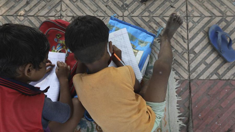 Veena Gupta, right, performs stretch exercises during a class for underprivileged children she conducts with her husband Virendra Gupta, in New Delhi, India, on Sept. 3, 2020. It all began when Veena's maid complained that with schools shut, children in her impoverished community were running amok and wasting time. The street-side classes have grown as dozens of children showed keen interest. Now the Guptas, with help from their driver, teach three different groups three times a week, morning and evening. As most schools in India remain shut since late March when the country imposed a nationwide lockdown to curb the spread of COVID-19, many switched to digital learning and taking classes online. (AP Photo/Manish Swarup)