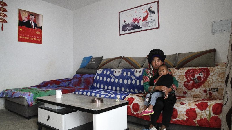 A Yi ethnic minority member stands inside his house displaying posters of Chinese President Xi Jinping and his wife Peng Liyuan, in Xujiashan village in Ganluo County, southwest China's Sichuan province, on Sept. 10, 2020. Communist Party Xi’s smiling visage looks down from the walls of virtually every home inhabited by members of the Yi minority group in a remote corner of China’s Sichuan province. Xi has replaced former leader Mao Zedong for pride of place in new brick and concrete homes built to replace crumbling traditional structures in Sichuan’s Liangshan Yi Autonomous Prefecture, which his home to about 2 million members of the group. (AP Photo/Andy Wong)