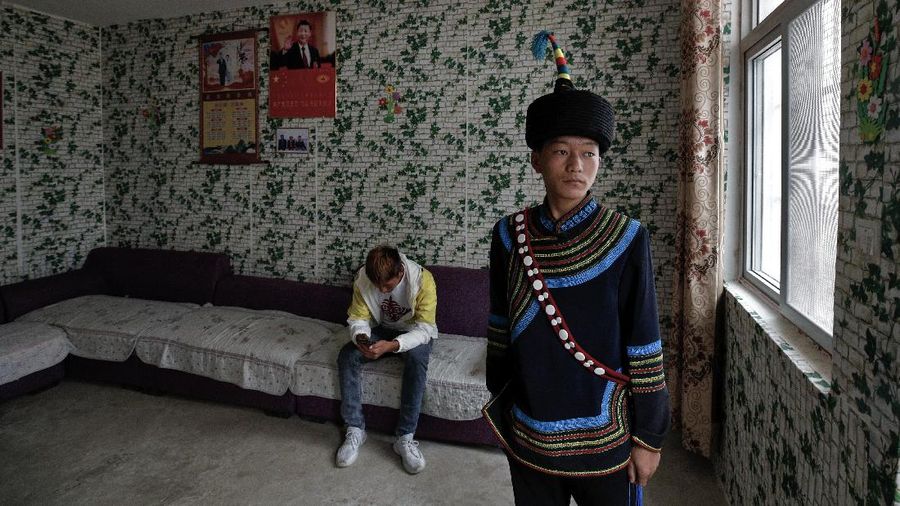 A Yi ethnic minority member stands inside his house displaying posters of Chinese President Xi Jinping and his wife Peng Liyuan, in Xujiashan village in Ganluo County, southwest China's Sichuan province, on Sept. 10, 2020. Communist Party Xi’s smiling visage looks down from the walls of virtually every home inhabited by members of the Yi minority group in a remote corner of China’s Sichuan province. Xi has replaced former leader Mao Zedong for pride of place in new brick and concrete homes built to replace crumbling traditional structures in Sichuan’s Liangshan Yi Autonomous Prefecture, which his home to about 2 million members of the group. (AP Photo/Andy Wong)